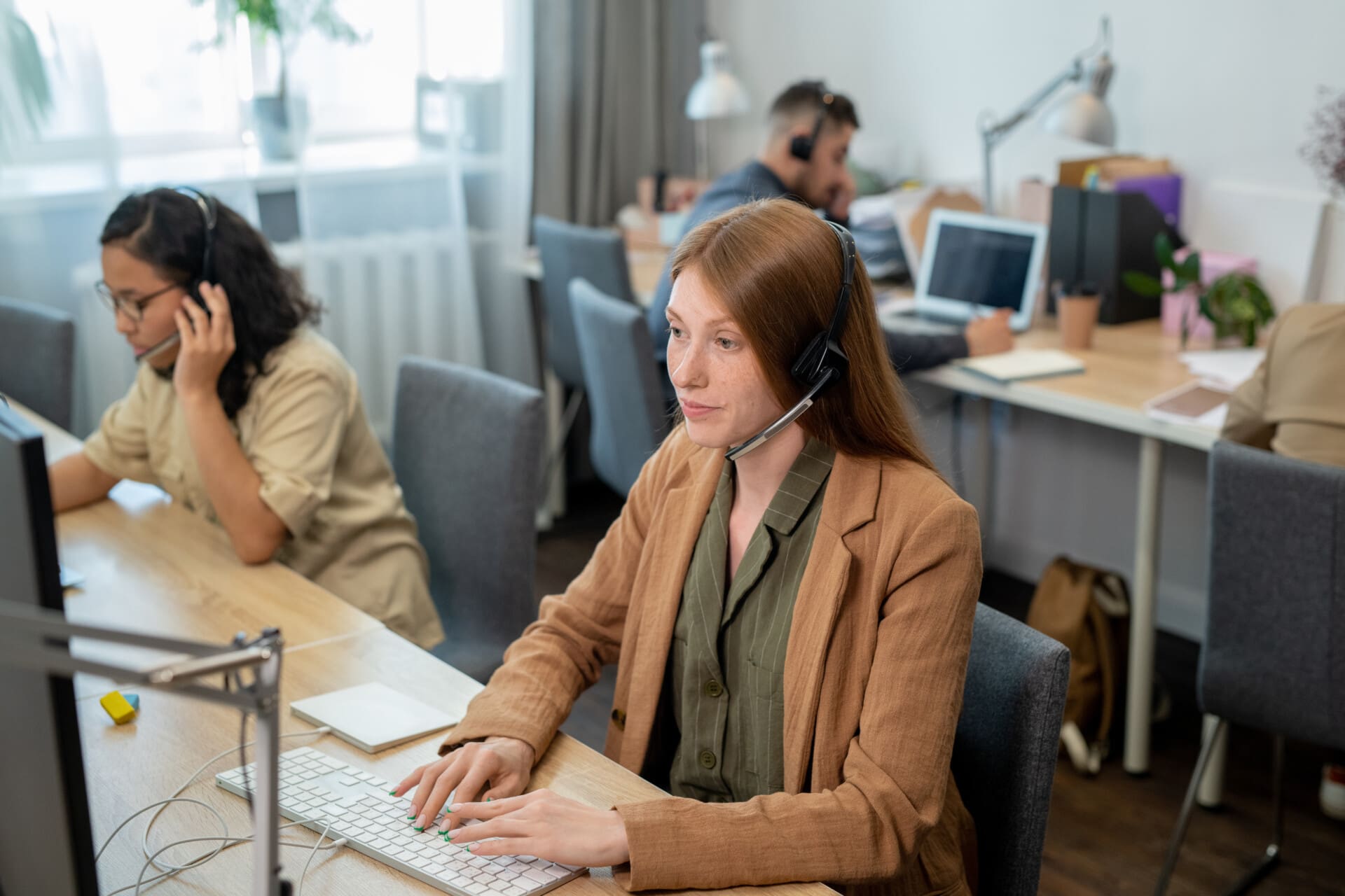 Young operator of call center consulting clients in front of computer