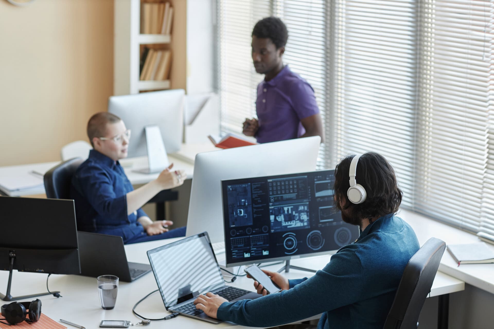 Young worker of cyber security center sitting in front of computers